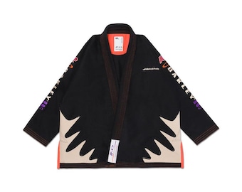 May include: Black martial arts gi with orange and tan accents. The gi features the text "OAKLEY" in purple and white on the sleeves. The gi has a white and tan design on the front and orange trim.