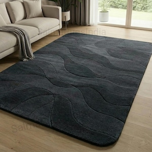 May include: A large, rectangular charcoal grey rug with a wavy pattern. The rug is placed on a light-coloured wooden floor, and a beige sofa is partially visible in the background. The rug's design adds a modern touch to the room.