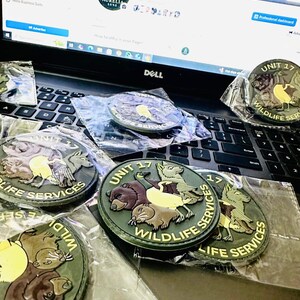 May include: Several circular patches with the text "UNIT 17 WILDLIFE SERVICES" and animal illustrations, including bears, beavers, and birds. The patches are in green, brown, and yellow, and are packaged in clear plastic.