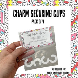 May include: A pack of four white plastic charm securing clips in a clear plastic bag. The bag has a label that says "South Made Simple" and includes the shop's Etsy website address. The text "*NOT REQUIRED FOR SOUTH MADE SIMPLE CHARMS" is printed below the bag.