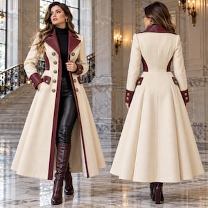 May include: A floor-length cream-colored coat featuring deep burgundy lapels, cuffs, and trim. The coat has a double-breasted front with gold-toned buttons, a fitted waist, and a flared skirt. It is worn over black pants and burgundy boots.