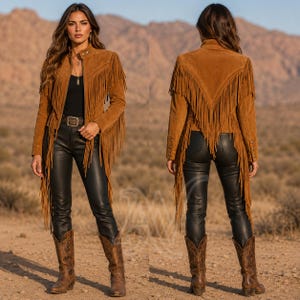 May include: A tan suede jacket featuring long fringe detailing along the chest, sleeves, and back. The jacket has a high collar, a front zipper closure, and long sleeves with buttoned cuffs. It is worn over a black top and black pants.