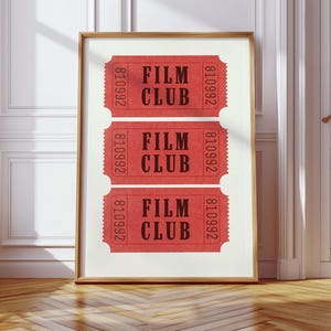 May include: Three red tickets with the text "FILM CLUB" and the number "810992" printed on them. The tickets are framed and hanging on a white wall.