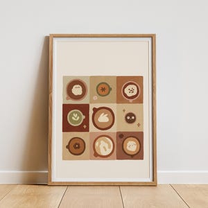 May include: A framed art print displaying a grid of nine coffee cup designs. Each cup features a unique latte art design, such as a flower, bunny, and other shapes. The colour scheme includes browns, tans, and greens.