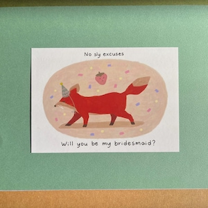 May include: A greeting card with a red fox wearing a party hat, with the text "No sly excuses" and "Will you be my bridesmaid?" The fox is surrounded by confetti and a strawberry illustration.