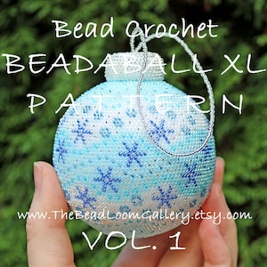 May include: A white, blue and silver beaded bauble with a snowflake pattern. The bauble is labelled "Bead Crochet Beadaball XL Pattern Vol. 1" and "www.TheBeadLoomGallery.etsy.com".