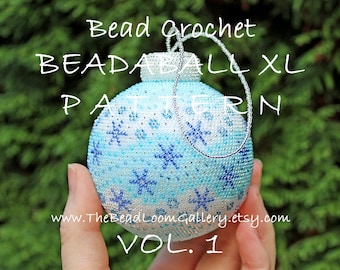 May include: A white, blue, and silver beaded ornament with a snowflake pattern. The ornament is labeled "Bead Crochet Beadaball XL Pattern Vol. 1" and "www.TheBeadLoomGallery.etsy.com".