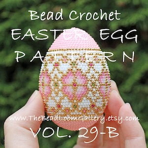 以下が含まれることがあります： ピンク、白、金色のビーズでできたイースターエッグのクロシェパターン。卵は幾何学模様で飾られており、手で持たれています。画像には「Bead Crochet Easter Egg Pattern Vol. 29-B」というテキストが表示されています。