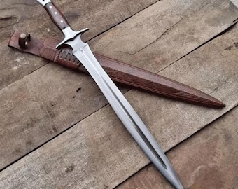 Könnte beinhalten: Ein langes, silbernes Schwert mit einem braunen Holzgriff und einem dekorativen Parierstück, das auf einer Holzoberfläche liegt. Das Schwert wird von einer braunen Lederscheide begleitet. Die Klinge ist scharf und spitz, und der Griff hat einen silbernen Knauf.