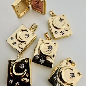 Peut inclure: Pendentifs dor&eacute;s en forme de livre avec un croissant de lune et des &eacute;toiles. Certains pendentifs sont ouverts, r&eacute;v&eacute;lant une petite image. Les pendentifs ont un th&egrave;me c&eacute;leste et sont probablement des bijoux.