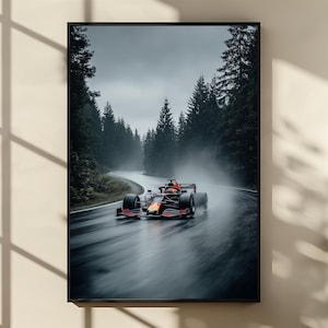 May include: A framed print of a Formula 1 race car speeding on a wet, winding road through a forest. The car is red and black, with a driver visible. The scene is captured in a realistic style, with a focus on speed and motion.