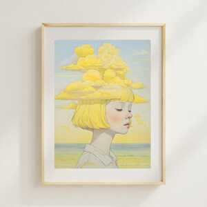 May include: A framed art print depicting a person with yellow hair and a cloud formation above their head. The illustration uses a soft palette of yellow, blue, and peach, with a beach scene in the background. The artwork is framed in a light wood.