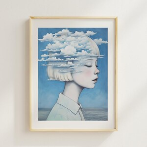 May include: A framed art print depicting a person with closed eyes, their head replaced by clouds. The artwork is set against a blue sky and ocean backdrop, framed in light wood, evoking a sense of calm and introspection.