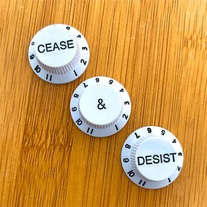 Perillas para guitarra con la leyenda "Cese y desista" (paquete de 3)