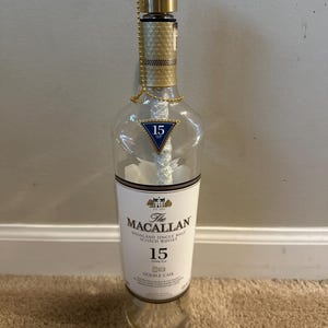 Op de afbeelding: Een doorzichtige glazen fles met een gouden dop en een etiket met de tekst "The Macallan Highland Single Malt Scotch Whisky 15 jaar oud Double Cask".