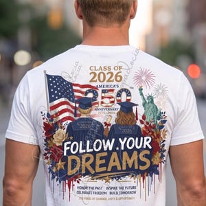 Op de afbeelding: Wit T-shirt met een patriottisch ontwerp. Voorzien van de Amerikaanse vlag, het Vrijheidsbeeld en de tekst "Class of 2026" en "Follow Your Dreams". Bevat de tekst "America's 250th Anniversary 1776-2026."