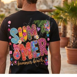 Op de afbeelding: Zwart t-shirt met een kleurrijk "SUMMER" ontwerp op de achterkant. Het woord "SUMMER" is versierd met bloemen, luipaardprint en geometrische patronen. De zin "Summer beach" staat eronder in cursief.