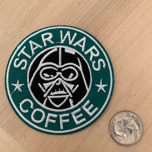May include: A green and white embroidered patch with the text "STAR WARS COFFEE" and a black and white image of Darth Vader's face in the center.