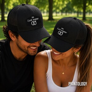 May include: Two black trucker hats featuring a hexagonal patch on the front. One hat displays the text MR. Last name with a wedding ring icon, and the other displays MRS. Last name with a wedding ring icon. Both hats have mesh back panels.