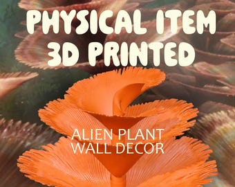 Puede incluir: Decoración de pared de planta alienígena impresa en 3D de color naranja. La imagen presenta un primer plano de una planta vibrante y estilizada con múltiples capas en forma de pétalos. El texto "PHYSICAL ITEM 3D PRINTED" y "ALIEN PLANT WALL DECOR" son visibles.