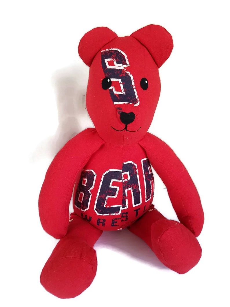 K&ouml;nnte beinhalten: Roter Pl&uuml;schteddyb&auml;r mit schwarzer Nase und Augen. Der B&auml;r tr&auml;gt ein rotes Shirt mit dem Aufdruck "BEAR WRESTLING" in Schwarz und Wei&szlig;.