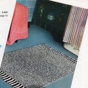 May include: A black and white striped bath mat with a textured surface. The mat is in a bathroom with a pink towel and a striped shower curtain.