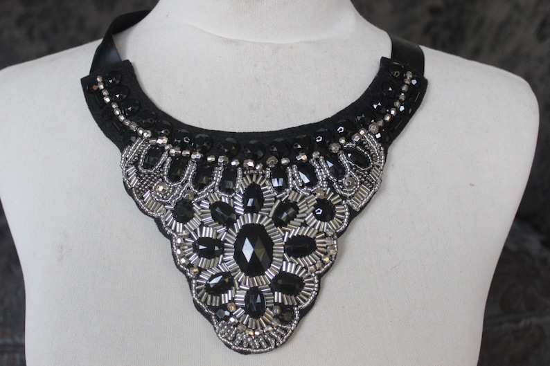May include: A black fabric choker necklace with silver and black beads and rhinestones.