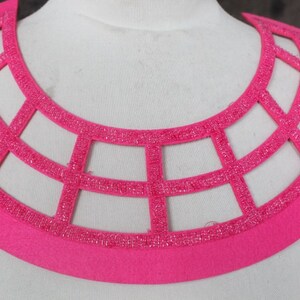 May include: A pink felt collar with a geometric design made of sparkly pink beads.