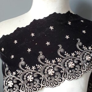 May include: Black velvet fabric with a scalloped edge and silver embroidery featuring a floral design.