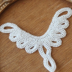 May include: A white pearl necklace with a delicate butterfly design. The necklace is made of small, round pearls that are strung together to create a delicate and feminine look.