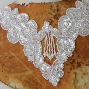 May include: White iridescent sequin and pearl trim with a beaded fringe. This trim is perfect for adding a touch of sparkle to any project.