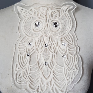 May include: White lace owl applique with rhinestone embellishments. The owl is detailed with intricate embroidery and has a delicate, feminine design.