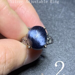 Puede incluir: Anillo ajustable de plata con una piedra de pietersita ovalada azul oscuro. La piedra mide 11 mm x 13 mm. El anillo tiene filigrana decorativa en los laterales y está sujeto por cuatro pequeñas garras.