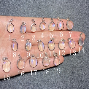 Puede incluir: Una colección de diecinueve colgantes de piedra lunar ovalados y en forma de lágrima con engastes plateados. Cada colgante tiene un brillo iridiscente único, con colores que van del blanco al azul y al melocotón. Los colgantes están numerados del 1 al 19.