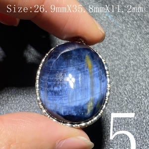 Puede incluir: Colgante ovalado de piedra preciosa azul con bisel plateado. La piedra presenta un patrón arremolinado con acentos amarillos y blancos. El colgante mide 2,69 cm x 3,58 cm x 1,12 cm.