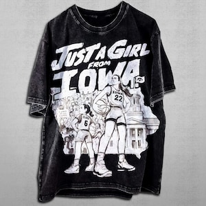 May include: Black t-shirt with the text "Just a Girl from Iowa" in white. The shirt features a graphic of two basketball players, the Iowa state outline, and the number 22. The shirt has a faded, vintage appearance.