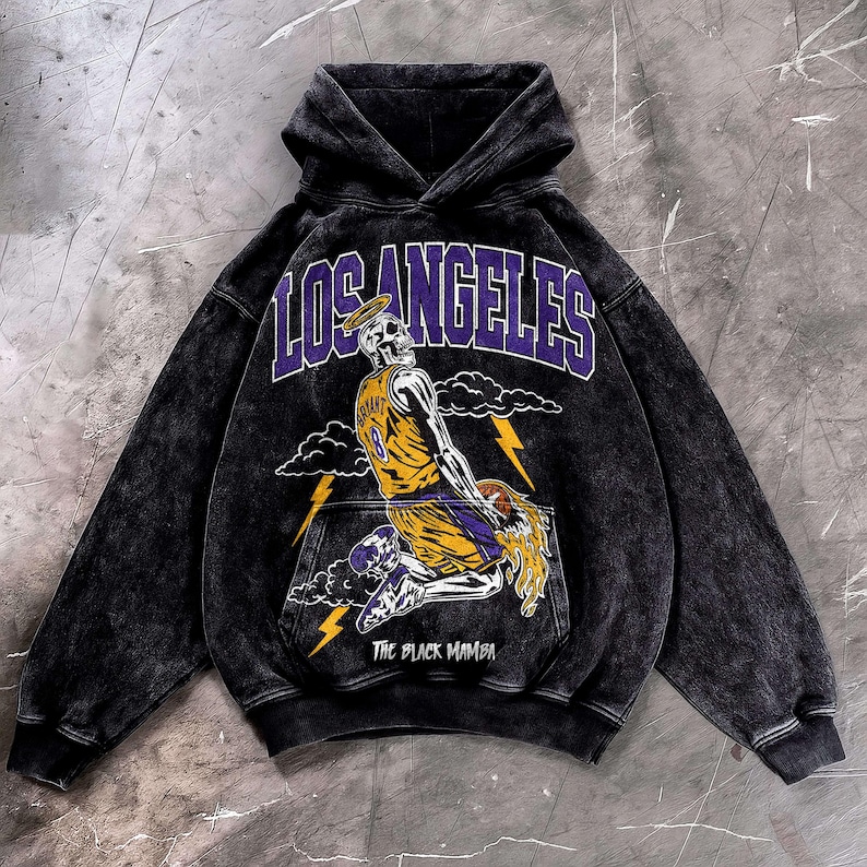 May include: Black hooded sweatshirt with a graphic of a skeleton wearing a basketball jersey with the number 8. The word "LOS ANGELES" is above the skeleton in purple letters. The text "THE BLACK MAMBA" is below the skeleton.