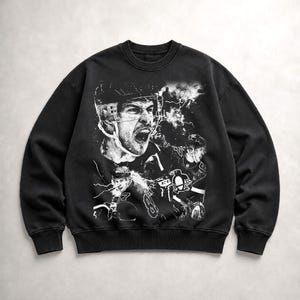 May include: A black crewneck sweatshirt featuring a large, white, high-contrast graphic print of a hockey player in a helmet with an open mouth, alongside a smaller player in a jersey with a penguin logo and the number 87, set against lightning.