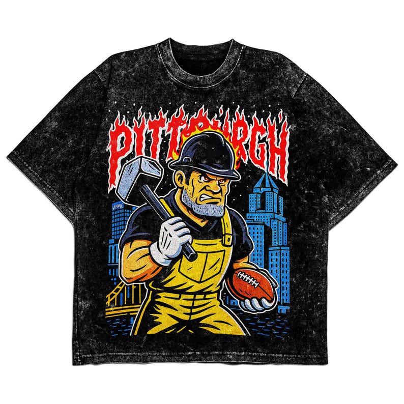 May include: Black acid wash t-shirt featuring a graphic of a construction worker holding a hammer and football, with the word "PITTSBURGH" in fiery letters. The worker wears a hard hat, yellow overalls, and white gloves. A cityscape is in the background.