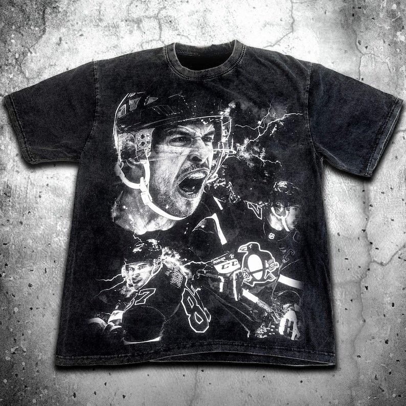 Pode incluir: Camiseta preta com uma estampa gr&aacute;fica branca de um jogador de hockey usando capacete e camisa. O gr&aacute;fico tamb&eacute;m inclui um logotipo de pinguim e raios.