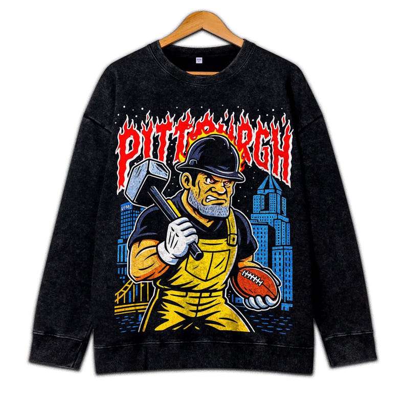 May include: Black sweatshirt with a graphic of a construction worker holding a hammer and football, with the word "PITTSBURGH" in red flames. The worker wears a hard hat, yellow overalls, and white gloves. A city skyline is in the background.