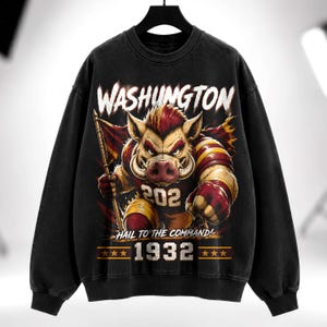 May include: A black crewneck sweatshirt featuring a graphic of a fierce boar wearing a maroon and gold jersey with the number 202. The text reads WASHUNGTON, HAIL TO THE COMMAND!, and 1932, accompanied by six gold stars on a maroon horizontal bar.