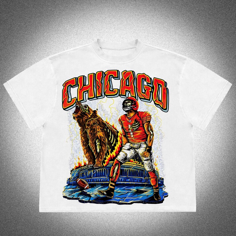 May include: White t-shirt with a graphic design featuring a football player and a bear, with the word "CHICAGO" in red and orange. The design includes a football, flames, and lightning bolts.
