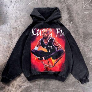 May include: Black hooded sweatshirt with a graphic of a basketball player in a meditative pose, holding a basketball. The words "Kung Fu" are above the image in white lettering. The player is wearing a black jersey with the number 1.