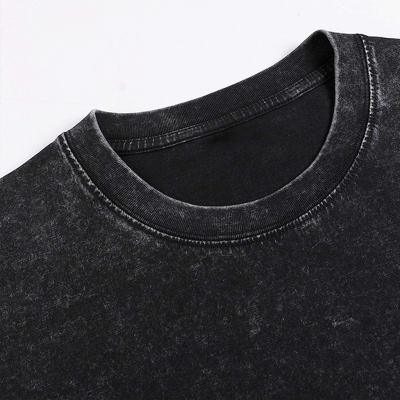 Pode incluir: Uma camiseta preta de gola redonda com um visual desgastado e vintage. O tecido tem uma apar&ecirc;ncia desbotada e desgastada.