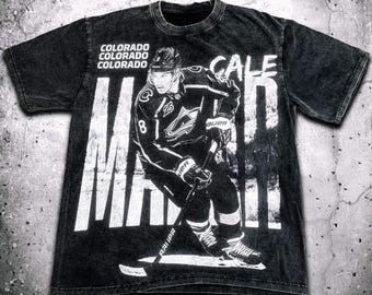 May include: Black t-shirt with a white graphic of a hockey player wearing a Colorado Avalanche jersey. The text "CALE MAKAR" is printed on the shirt.