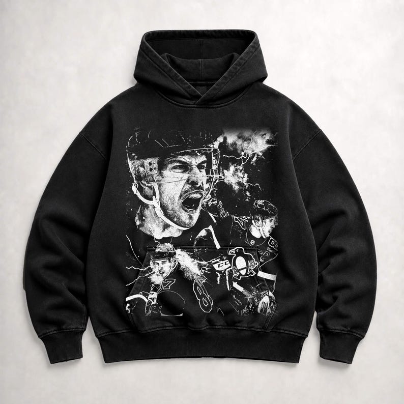 May include: A black hooded sweatshirt featuring a large, detailed white graphic print on the front. The design depicts multiple hockey players in action, including a prominent close-up of a player shouting, alongside a Pittsburgh Penguins logo.