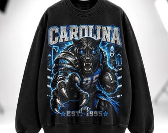 Camiseta vintage de futebol americano da Carolina, camiseta com estampa "704 Warrior", estilo streetwear americano, camiseta preta oversized com capuz e lavagem desbotada.