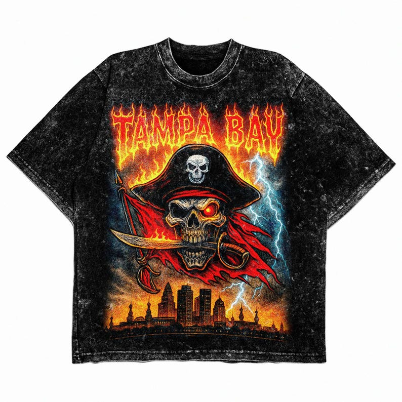 May include: Black t-shirt with a distressed effect, showcasing a pirate skull wearing a hat and holding a sword. The design includes the text "TAMPA BAY" in fiery lettering, a cityscape, and lightning bolts.