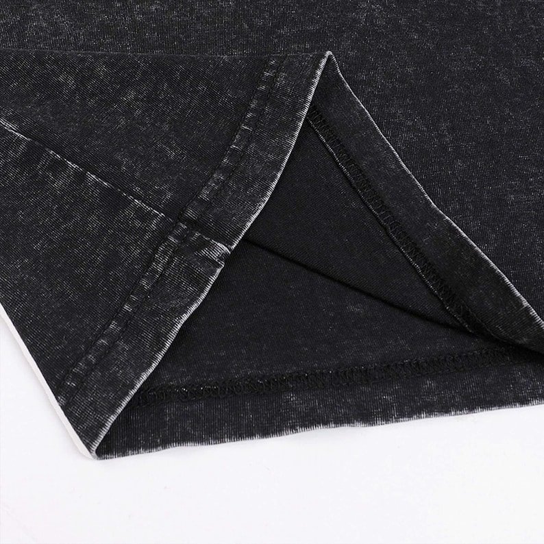 Pode incluir: Close-up da costura interna de uma pe&ccedil;a de roupa preta. O tecido tem um aspeto desgastado e vintage.